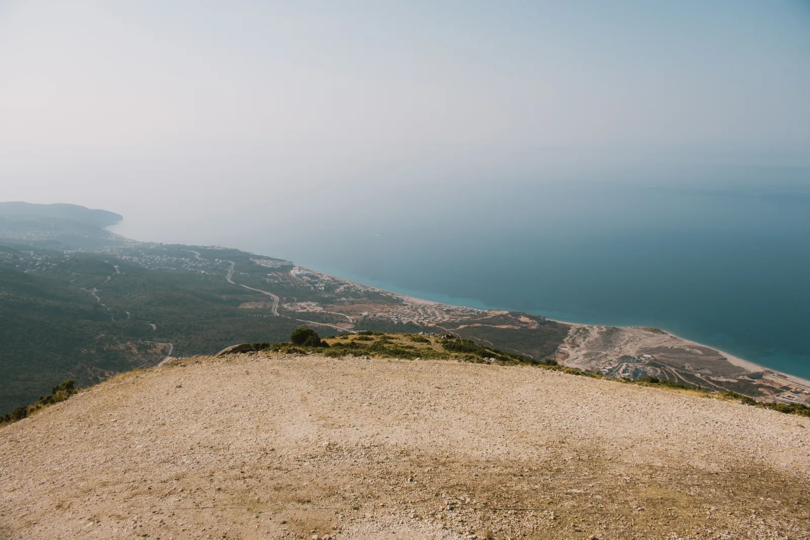 מבט מרמה חשופה מעל הריביירה האלבנית אל קו החוף והים באובך בוקר
