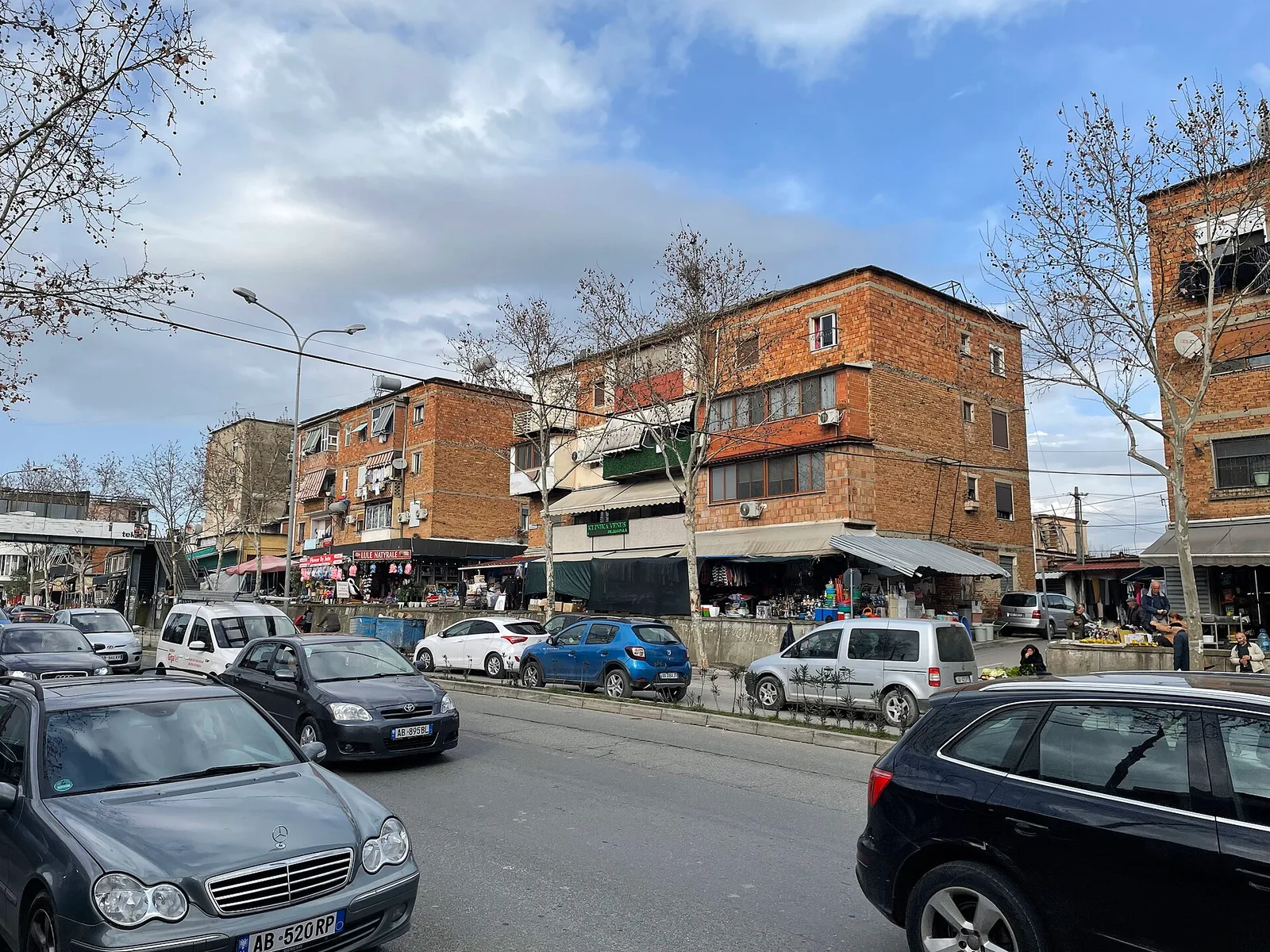 רחוב עירוני שוקק באלבניה עם שוק וחנויות