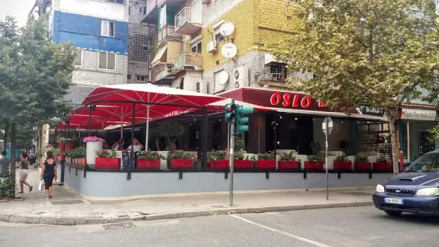 פינת רחוב עם סוככים ושמשיות אדומות, אדניות פרחים ובנייני מגורים מאחור