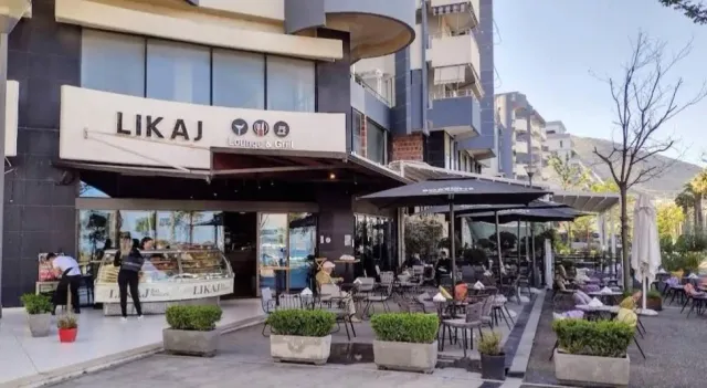 חזית עסק עם שילוט מואר, ויטרינת מאפים ומרפסת עם שמשיות שחורות