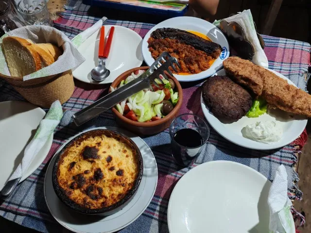 שולחן עמוס סלסלת לחם, סלט בקערת חרס, קדרת מאפה וצלחת קציצות