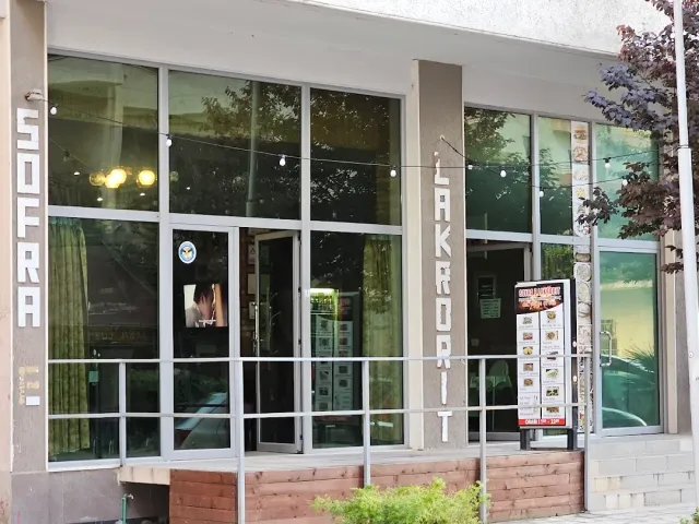 חזית מבנה עם חלונות גדולים, שלטים אנכיים, נורות תלויות ולוח תפריט בכניסה
