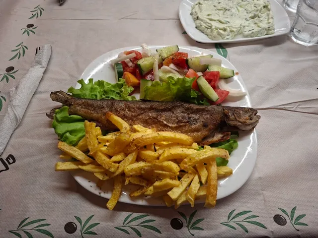 דג פורל מטוגן שלם עם צ׳יפס וסלט ירקות על מפה עם עלי זית