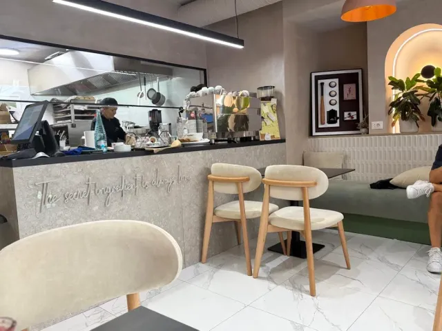 חלל פנימי עם דלפק, מטבח פתוח מאחוריו וכיסאות מרופדים בגוון שמנת