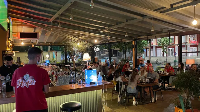 בר ערב מקורה עם ברזי בירה, סועדים ליד שולחנות ותאורה חמימה