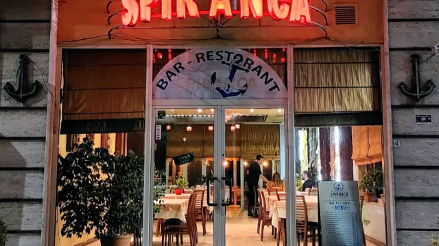 חזית אבן עם שלט ניאון אדום, דלתות זכוכית ואולם מסודר בפנים