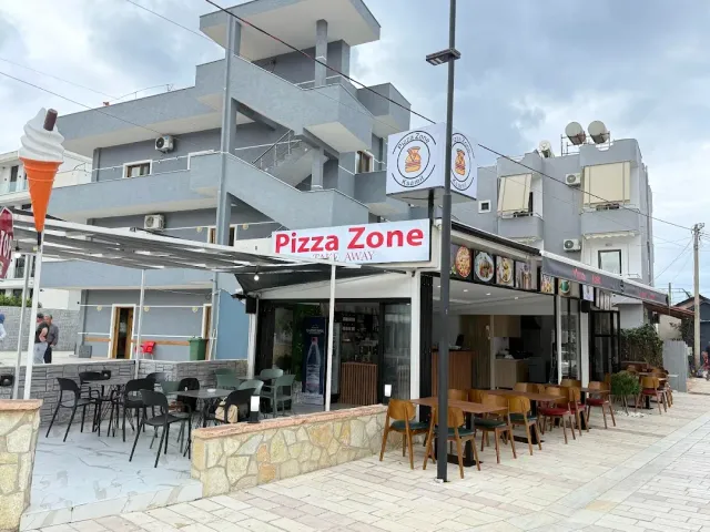 פינת רחוב עם שלט אדום, סככה, כיסאות בחוץ ופסל גלידה גבוה