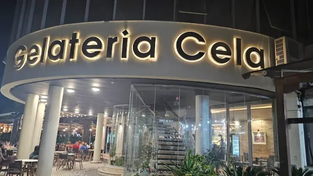 שלט מואר גדול מעל כניסה מעוגלת עם עמודים, וישיבה חיצונית בלילה