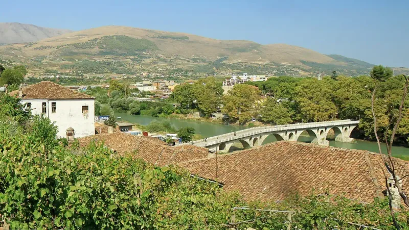 גשר אבן מקושת בין גגות רעפים לגבעות