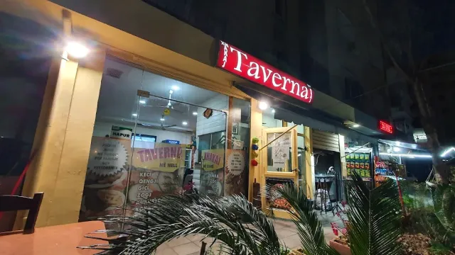 חזית זכוכית בלילה עם שלט אדום מואר ומודעות, וכפות דקל בחזית
