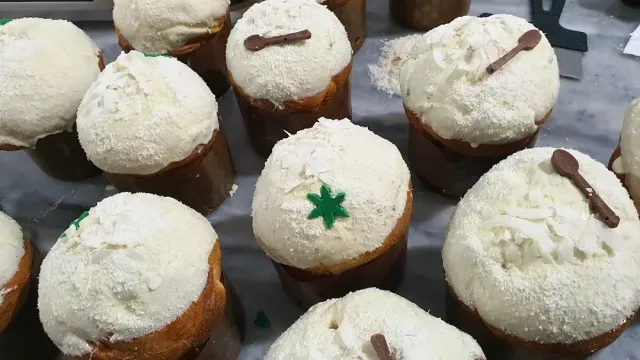 עוגות שמרים אישיות מכוסות קרם לבן ושבבי קוקוס, מעוטרות בכפיות שוקולד