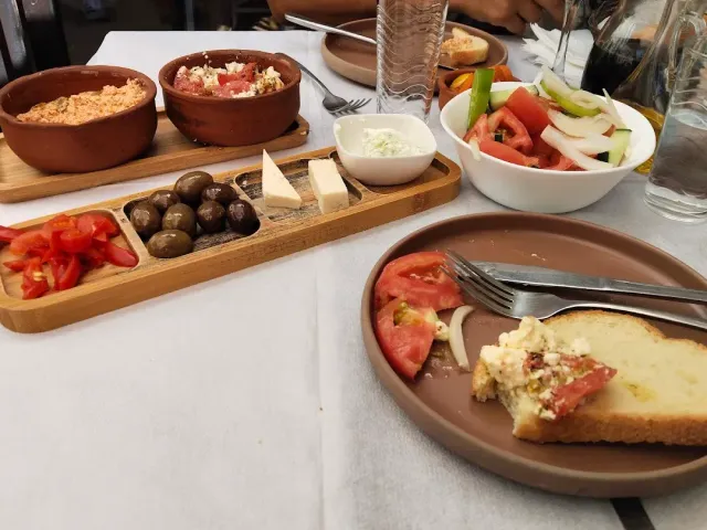 שולחן עם קעריות חרס של ממרחים, קרש זיתים וגבינות וקערת סלט ירקות